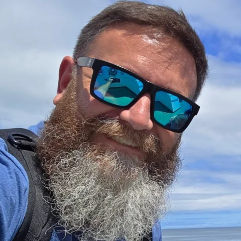 Mark Main, Ledge Rock HOA board member, smiling in sunglasses with the ocean behind him