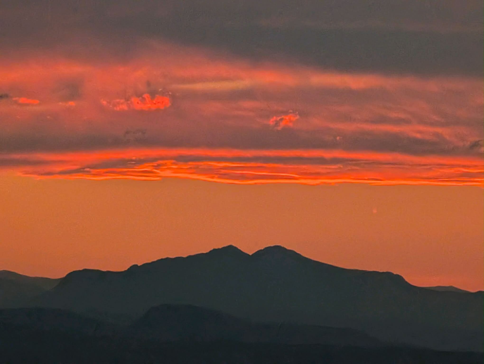 A blazing orange sunset over the silhouette of the Rocky Mountains, seen from Ledge Rock