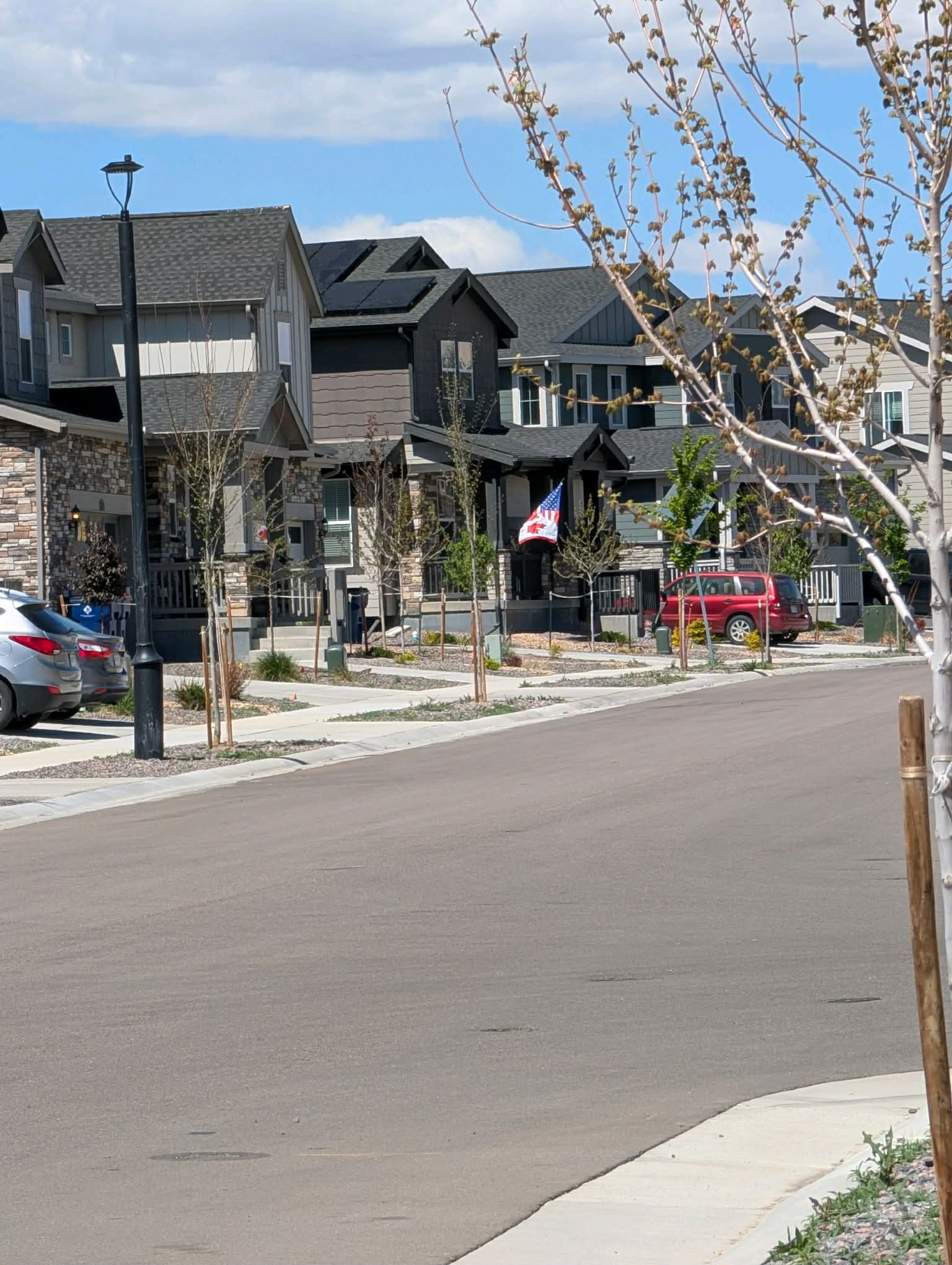 A Ledge Rock street — craftsman-style homes with front porches, young trees, and a flag flying